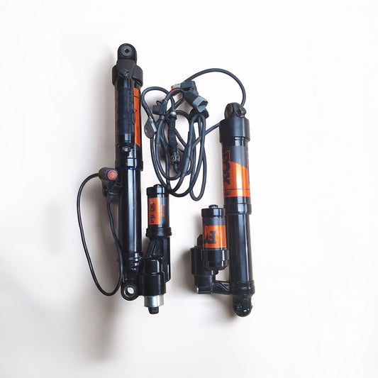 A set of black air front suspension shock absorbers with orange  Fox branding, shown on a clean white background.