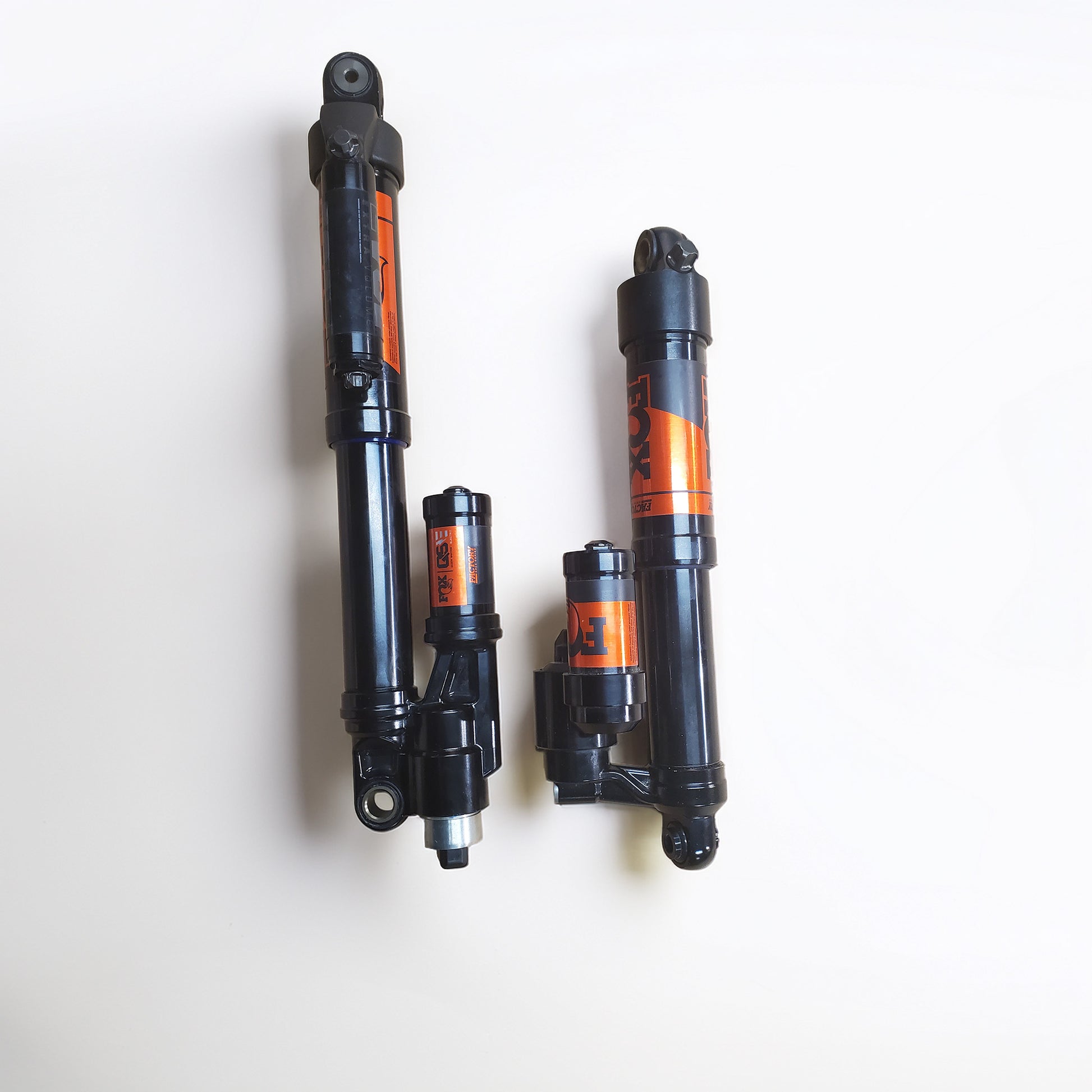Three black snowmobile shock absorbers with orange and black Fox branding, arranged vertically on a plain white background.