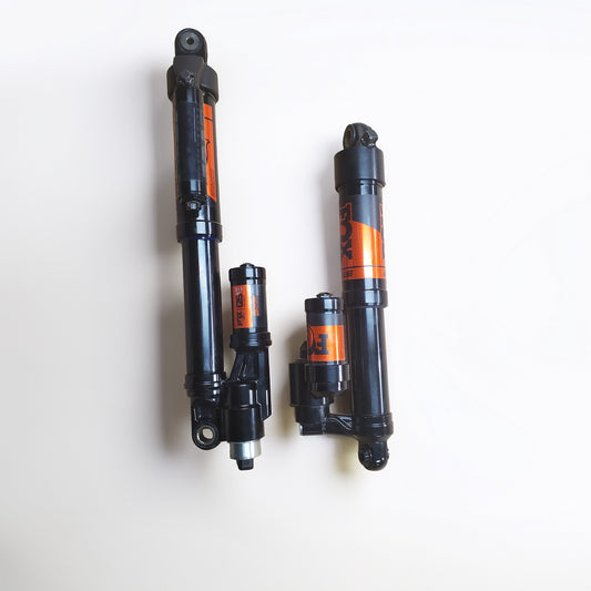 Three black snowmobile shock absorbers with orange and black Fox branding, arranged vertically on a plain white background.