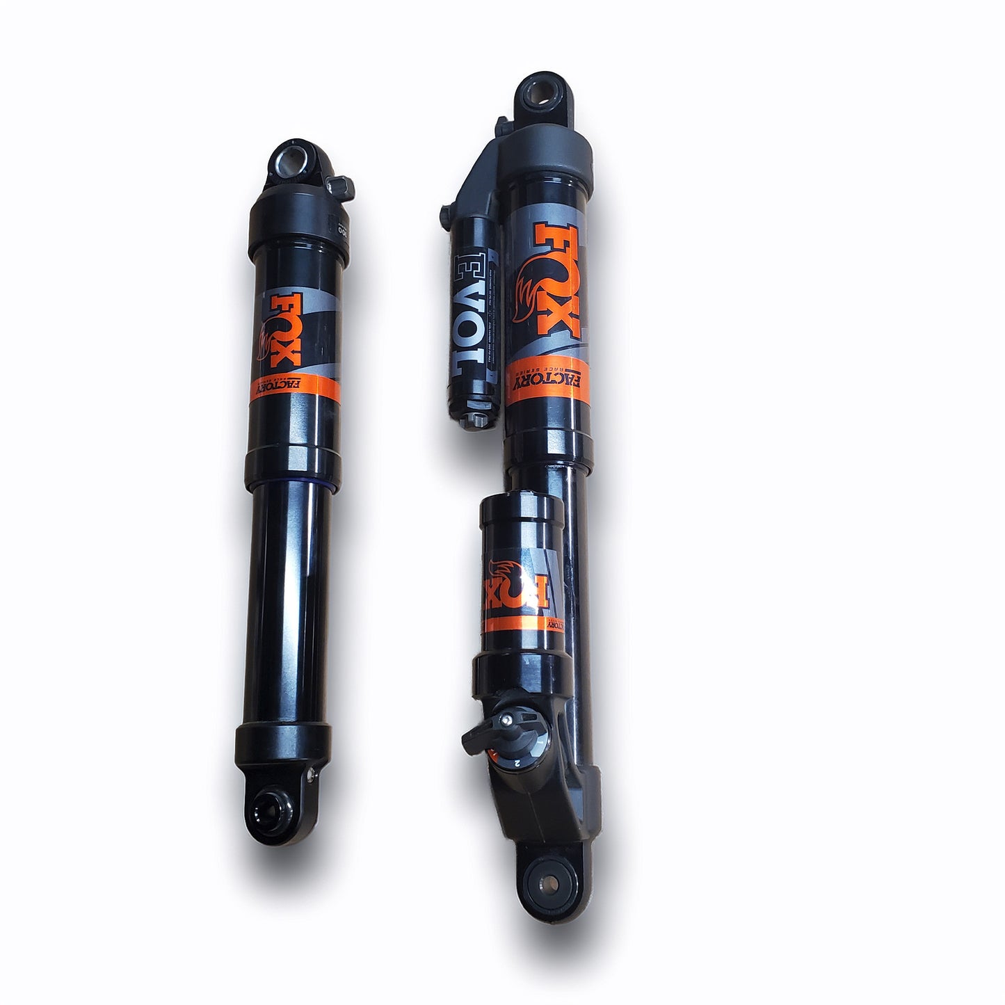 Two black Fox Evol shock absorbers shown upright on a white background, one in front view and one in side profile, both featuring orange and gray Fox branding.